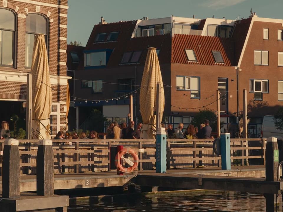 Mensen op een terras aan het water in de late middagzon